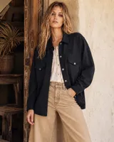 Camisa tejida en lana merino color negro, de corte oversize, con mangas largas, bolsillos con solapa en el pecho y cierre frontal de botones.