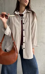 Sobrecamisa de pana color natural, con corte oversize, cuello camisero, cierre frontal de botones oscuros y mangas largas con puños abotonados.