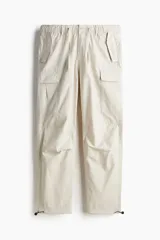 Pantalón cargo color beige de corte recto en tejido ripstop, con cintura elástica ajustable con cordón, bolsillos laterales, traseros y en las piernas con solapa y botón a presión, y elástico en los bajos.