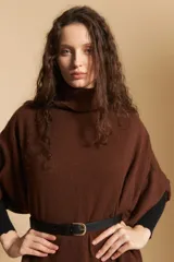Poncho tejido de color marrón con cuello alto y mangas amplias de diseño holgado.
