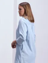 Vestido camisero corto celeste de algodón y viscosa, con cuello camisero, escote en V, mangas tres cuartos con botón y bolsillos laterales.
