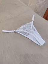 Conjunto de lencería compuesto por un bralette triangular de encaje floral con breteles regulables y una bombacha tipo tanga a juego con detalles de encaje y tiras ajustables.