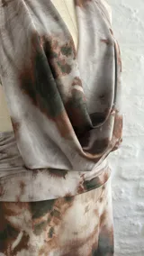 Vestido largo de microtul con estampado abstracto en tonos marrones y blancos, escote halter pronunciado, espalda descubierta y aberturas laterales en la cintura.