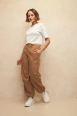 Pantalón babucha tipo parachute color beige, de nylon, con cordones ajustables en la cintura y en los tobillos.