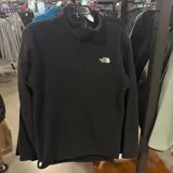 Campera de polar negro con cierre frontal parcial y cuello alto. Presenta el logo de la marca bordado en blanco en el pecho.