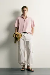 Polo de corte regular fit en color rosado con efecto lavado. Presenta cuello solapa, cierre frontal de botones y mangas cortas con acabados en rib.