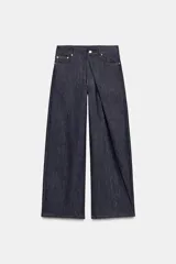 Jeans de tiro medio, pierna relajada y largo completo, color azul oscuro. Presenta cinco bolsillos, detalle de pliegue delantero y pespuntes marcados a contraste.