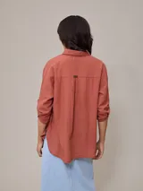 Camisa color beige de algodón y lino, con cuello clásico, cierre frontal con botones, mangas largas con puños abotonados, dos bolsillos con solapa en el pecho y corte holgado.