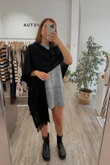 Ruana tejida color negro con diseño calado y flecos en los bordes.