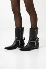 Botas de cuero negras de caña media con punta fina, taco de 8cm y detalle de cadena plateada.