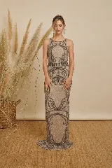 Vestido largo color gris, confeccionado con bordado artesanal de canutillos y lentejuelas en tono oscuro con diseño geométrico y arabescos, de silueta al cuerpo y sin mangas.