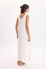Vestido largo blanco sin mangas, con escote en V y pinza frontal que aporta un diseño de caída suelta.