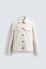 Sobrecamisa regular fit color beige, confeccionada en tejido efecto ante. Cuenta con cuello solapa, manga larga con puño abotonado, bolsillos de plastrón con solapa en el pecho y bolsillos de vivo en la cadera. El cierre es frontal con botonadura de botones negros.