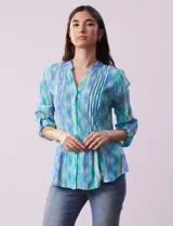 Blusa de gasa estampada con cuello a la base, escote en V y abertura central con botones. Delantera con plisados y mangas 3/4 regulables con presilla y botón.