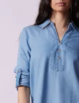 Blusa de lyocell color azul claro, con cuello camisero, escote en V con tapeta de botones y mangas largas con presilla para regular el largo.