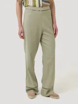 Pantalon de lino organico color verde militar, de corte recto y tiro alto, con detalles de calado negro en la cintura y en los dobladillos.