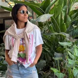 Remera blanca de corte holgado con estampa frontal colorida que incluye rayas verticales rosadas y un diseño gráfico de un trago con rodaja de naranja. Confeccionada en mezcla de algodón y poliéster.