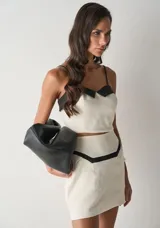 Top de tirantes finos con diseño bicolor, confeccionado en color crudo con detalles en negro en el escote. Presenta un corte ajustado y estilo corset.