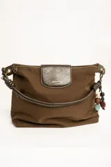 Cartera tipo shopper color marrón, con solapa frontal decorativa en tono más oscuro y tiras con nudos. Incluye herrajes dorados y un charm colgante con cuentas de madera.