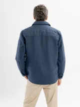 Tapado de paño en color azul, con diseño de sobrecamisa, cierre frontal con botones, cuello clásico y bolsillos frontales con solapa.