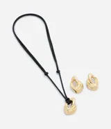 Conjunto de bijouterie compuesto por collar con cordón negro ajustable y dije colgante de metal dorado con diseño orgánico, acompañado de caravanas a juego.