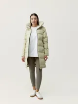 Campera larga tipo puffer de color beige, con acabado mate, cuello alto envolvente y cierre frontal con cremallera. Presenta diseño de bandas acolchadas termoselladas, bolsillos laterales con cierre oculto y relleno vegano.