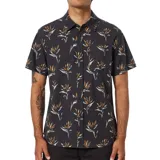 Camisa de manga corta con estampado de flores de ave del paraíso en tonos naranja y blanco sobre fondo negro. Tiene cuello clásico, cierre con botones y bolsillo en el pecho.