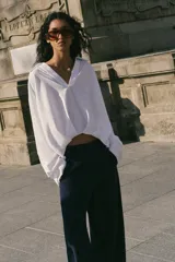 Camisa verde militar confeccionada en mezcla de lino, con cuello solapa, escote en pico, manga larga y diseño asimétrico con pliegues en la parte delantera.