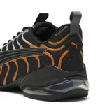 Championes Puma modelo Voltra, de diseño deportivo con tecnología X-CELL en la suela. Presentan una base de malla negra con detalles superpuestos en gris y naranja, incluyendo el logo de la marca en el frente.