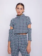 Top corto de tejido con estampado geométrico retro en tonos rosa, gris y negro. Es de manga larga con cut-out en los codos y cuello alto.