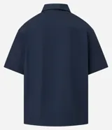 Camisa de manga corta color azul marino de corte boxy, con cuello inglés, cierre frontal de botones metálicos a presión y bolsillos cargo en el pecho.