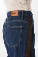 Jean de pierna ancha color azul con detalles en los laterales con estampado animal print marrón, de tiro alto y bolsillos plaqué en la espalda, marca Petra.