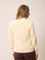 Cardigan de punto color azul, con cierre frontal completo, cuello alto y mangas largas con puños acanalados.