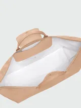 Bolso de viaje de gran tamaño, modelo Le Pliage One de Longchamp, en color marrón. Presenta el diseño icónico de la marca con solapa de cuero, asas cortas y cierre de cremallera superior.