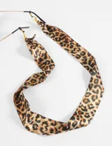 Correa para lentes de tela satinada con estampado animal print. Incluye ganchos metálicos dorados en los extremos para sujetar a las patillas de los lentes.