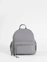 Mochila mediana de nylon color gris, con cierre frontal y tiradores decorativos con nudos. Cuenta con compartimento principal con cierre y asa superior.