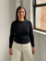Sweater de punto negro con diseño de trenzas verticales, cuello redondo y mangas largas ajustadas.
