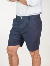 Bermuda color beige confeccionada en lino, con bolsillos laterales y traseros, y presillas para cinturón.