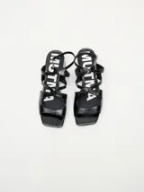 Sandalias de cuero con acabado de charol en color bordó, con diseño de tiras cruzadas, punta cuadrada y taco bloque de 4,5 cm. Incluyen correa ajustable con hebilla en el tobillo.