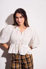 Blusa negra de algodón con diseño de broderie, mangas tres cuartos abullonadas, cierre frontal con botones y detalle de cordón ajustable en la cintura.