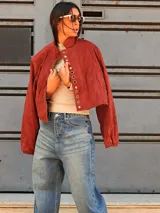 Campera tipo bomber color bordó, confeccionada en gamuza, con cierre frontal y una hilera de botones metálicos decorativos a lo largo de la solapa. Presenta mangas largas con puños holgados y un diseño de corte oversize.