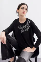 Sweater negro de manga larga y calce holgado, con terminaciones en punto rib. Presenta un bordado frontal con la frase "Tonight the night" realizado con canutillos y piedras de colores.