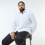 Camisa de manga larga con corte regular fit, color blanco con estampado de pequeños puntos negros. Presenta cuello clásico y cierre frontal con botones.