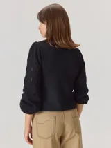 Buzo de lana color negro con mangas abullonadas y diseño de calado en forma de rombos. Presenta un tejido de punto con textura y corte clásico.