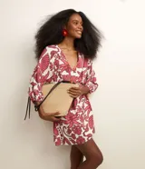 Salida de playa corta confeccionada en viscolino con estampa floral en tonos fucsia sobre base blanca. Tiene escote en V cruzado, mangas largas con elástico en los puños y lazo lateral.