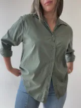 Camisa celeste de corte holgado, con cuello clásico, cierre frontal con botones, bolsillo en el pecho y mangas largas con puños abotonados.