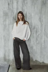 Sweater de punto blanco con textura acanalada horizontal, cuello barco, mangas largas amplias y corte holgado.