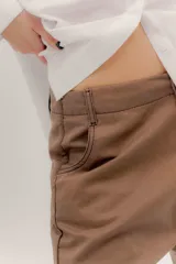 Pantalón de denim oscuro con tiro bajo y calce relajado. Presenta un cierre frontal con botones a la vista y costuras en contraste.