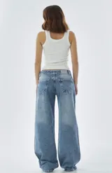 Jean wide leg de tiro bajo, confeccionado en denim de tono azul claro con efecto lavado. Presenta un corte holgado y relajado en las piernas, con cierre frontal y bolsillos clásicos.