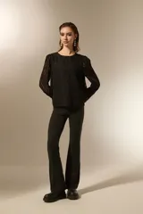 Blusa negra de poliéster con diseño texturizado de ondas, cuello redondo a la base y mangas largas transparentes con puños elásticos.